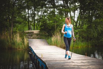 Pregnant woman nordic walking outdoor, exercises during pregnancy