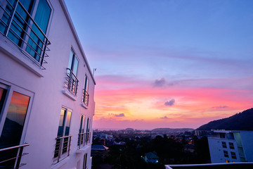 Beautiful sunset in town. Bright sky behind the white building.