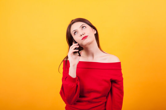 Portrait of beautiful young woman bored talking on the phone over yelloq background