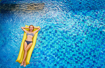 Enjoying suntan. Vacation concept. Top view of slim young woman in bikini on the yellow air...