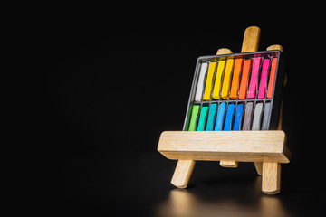 Chalk color on the realistic wooden easel with black background.