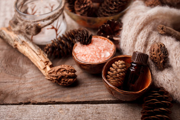 Wood scents for winter time aromatherapy. Pine cones, candles, essential oil bottles, top view. Spa relax winter concept, copy space