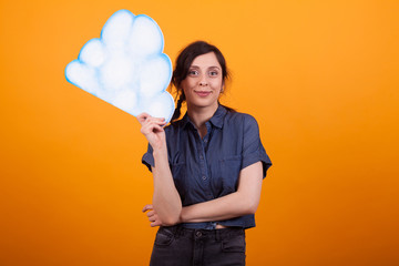 Attractive young woman holding an idea cloud in studio over yellow background