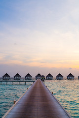 Beautiful tropical sunset over Maldives island with water bungalow in hotel resort