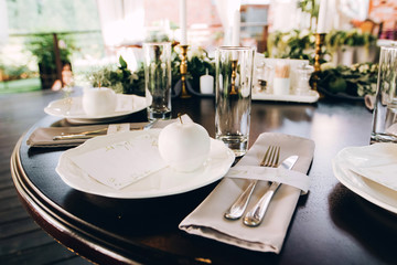 Boho wedding table setting, rustic decorations, gold and blue details, wooden table, bokeh. Luxury wedding decor. Monstera leaves and orchid flowers.