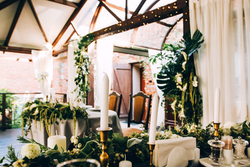 Boho wedding table setting, rustic decorations, gold and blue details, wooden table, bokeh. Luxury wedding decor. Monstera leaves and orchid flowers.