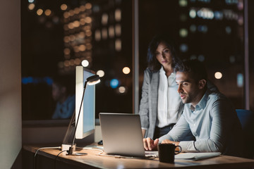Two focused colleagues working in an office late at night