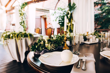 Boho wedding table setting, rustic decorations, gold and blue details, wooden table, bokeh. Luxury wedding decor. Monstera leaves and orchid flowers.