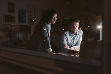 Two young businesspeople working late together in an office