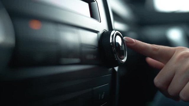 Female hand turn on air conditioning in the car