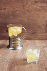 glass of water with lemon on wooden background