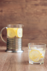 glass of water with lemon on wooden background