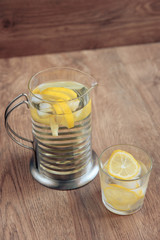 glass of water with lemon on wooden background