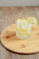 glass of water with lemon on wooden background