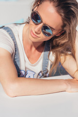 Naklejka premium Successful young woman in sunglasses happily resting and sunbathing in the sun near the sea while relaxing on a sunny hot summer day. Long-awaited vacation concept