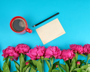 red creameric cup with black coffee and a bouquet of red peonies with green leaves
