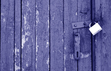 Old padlock on wooden gate in blue tone.