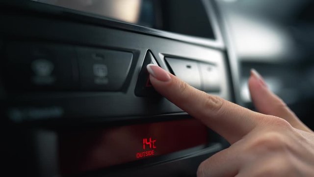 Finger of unrecognizable woman presses the alarm button - emergency signal in car.