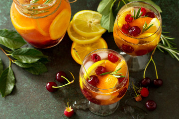 Homemade refreshing wine sangria or punch with fruits. Sangria cocktails with fresh fruits, berries and rosemary on dark a stone or slate background.