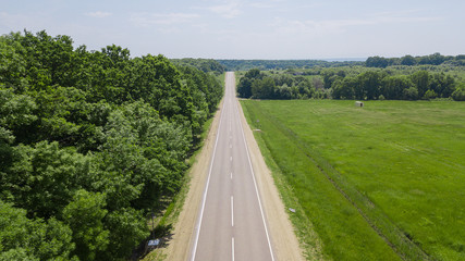 Scenic country road between dense forest and fields