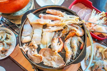 The group of seafood and meat grilled on the hot pot during BBQ time in the restaurant. 