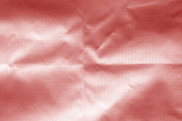 Crumpled transparent plastic surface in red color.