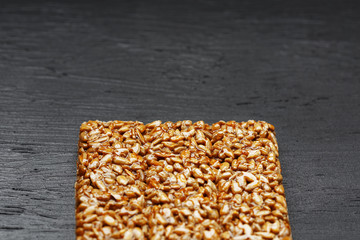 Tile kozinaki from sunflower seeds on a black textural background. Delicious oriental sweets...