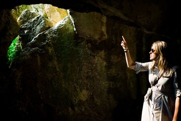 Woman pointing and hole in the ancient cave - sunlight