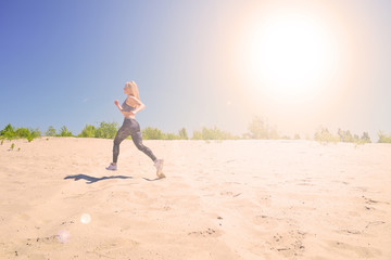 Young blonde girl running on sand in desert. Outdoor sports.