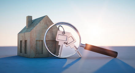 Haus mit Schlüsseln und Lupe im Sonnenuntergang