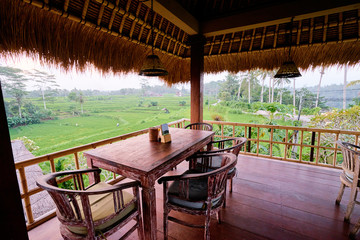 Wooden terrace of cafe with beautiful green rice fields view. Bali, Indonesia.