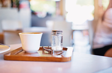 White cup of coffee and glass sugar bowl on the table.