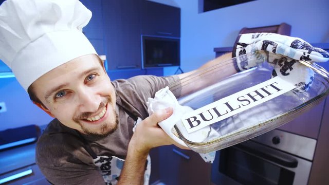 Cook baking some bullshit in glass baking dish 4K. Wide view close-up on person face and dish in focus, smiling into the camera with kitchen in the background out of focus.