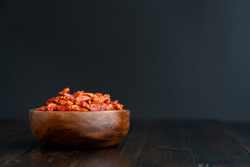 Dried bird's eye chili peppers in a wooden bowl. Dark wooden table, high resolution, negative space