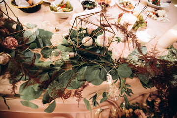 Wedding. Banquet. Beautiful and creative composition of a variety of pale pink flowers and candles that decorated the table for the newlyweds. Modern wedding decoration with geometric elements.