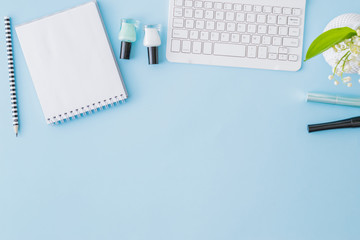 Flat lay blogger or freelancer workspace with a notebook, keyboard and lily of the valley flowers on a blue background © maria_lh