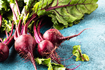 Großaufnahme von frischen reifen ungekochten roten Rüben (rote beete )auf blauer Oberfläche