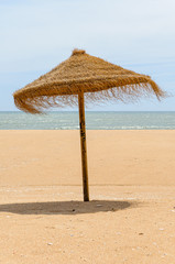 Straw parasol on a sandy beach.