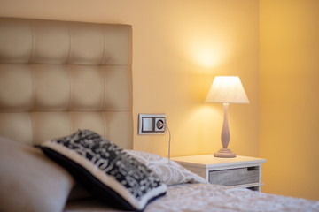 Cozy bedroom interior with book and reading lamp on bedside table