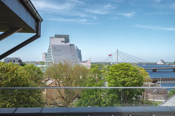 Panoramic view of Riga city covered in clouds. Iconic railroad bridge and old town panorama across the river  Daugava. Picturesque scenery of historical architecture. National library of Latvia.