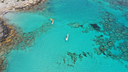 Aerial top view photo of men practising wind surfing in exotic paradise open ocean bay with crystal clear turquoise sea