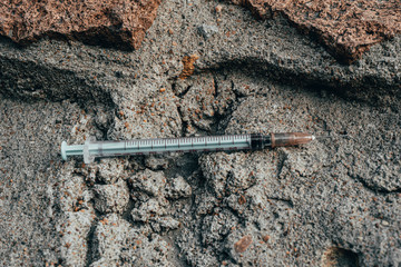 used syringe on concrete, drug addiction