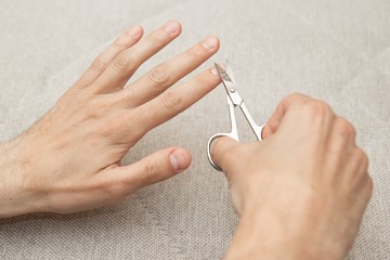 Nail trimming. Nail scissors in hand. Body care, manicure.