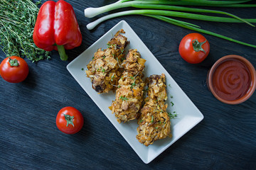 Roasted chicken drumsticks on a plate. Breaded chicken drumsticks, fried chicken. Dark wooden background.