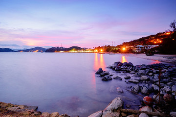 Fototapeta premium Peaceful evening on the bay. Beautiful landscape with sea, embankment, purple sky and city lights.