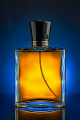bottle of men's perfume yellow on a blue background with a reflection