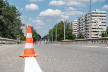 Traffic cone, Orange traffic safety cone barriers on the street protect fresh white paint marking on dividing asphalt road driving lanes low point of view
