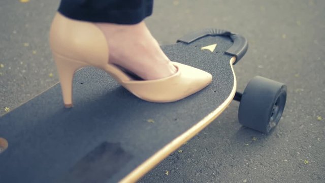 close-up. women's beige shoe on a black skate board. Modern business woman in beige pumps shoes, rides on an electric board along a city street. The concept of achieving the goal and leadership