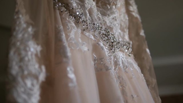 Close-up of hanging wedding dress ivory embroidered with rhinestones.