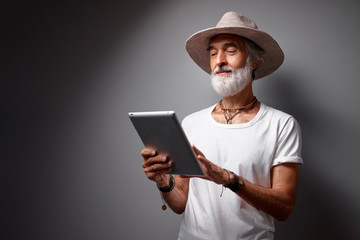 Studio portrait of handsome senior man using tablet computer.